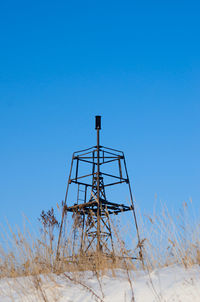 Low angle view of tower on field against clear blue sky