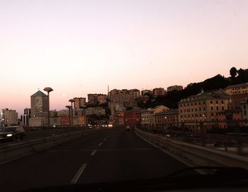 City street by buildings against sky during sunset