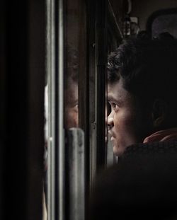 Side view of mid adult man looking at window in train