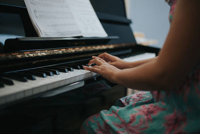 Midsection of girl wearing dress while playing piano