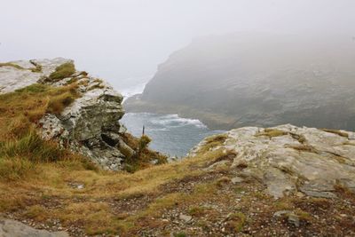 Scenic view of sea by cliff against sky