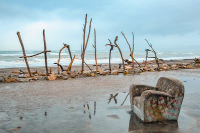 Wooden posts on beach against sky