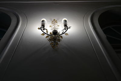 Low angle view of illuminated electric lamp hanging on ceiling