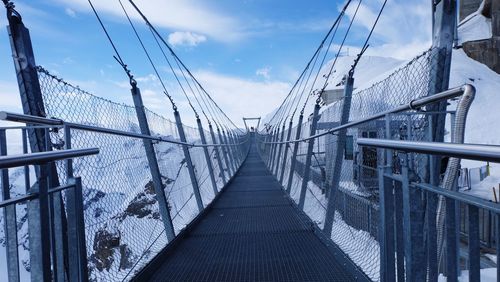 Footbridge against sky during winter