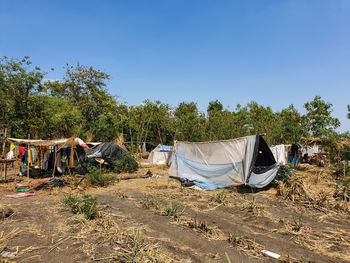 Clothes drying on clothesline against trees against clear blue sky