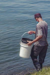 Man holding bucket standing in water