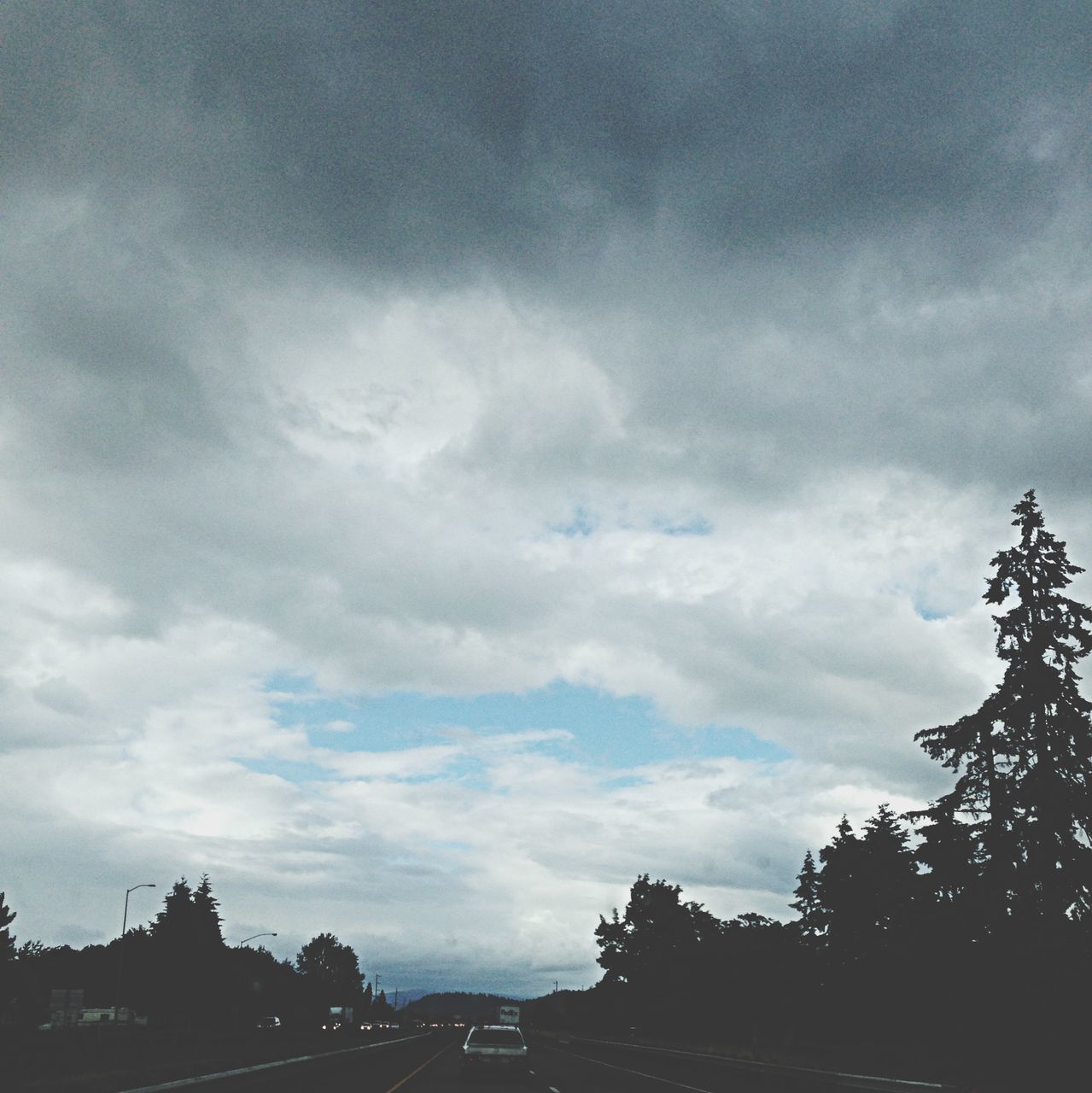 tree, sky, transportation, cloud - sky, road, car, cloudy, land vehicle, silhouette, street, the way forward, low angle view, cloud, nature, mode of transport, outdoors, weather, dusk, no people, tranquility