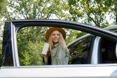 Side view of woman taking selfie through car