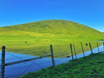 Low angle view of green landscape against blue sky