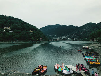 People on river by mountains against sky