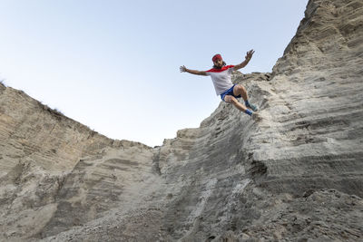 One man runs down on a very steep wall at an old mining waste of sand