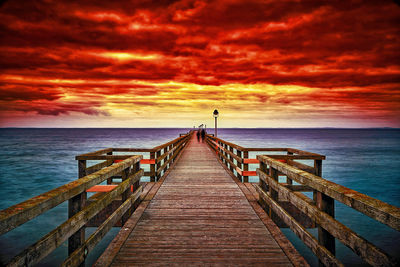 Pier over sea against sky during sunset