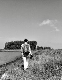 Rear view of man standing on field against sky