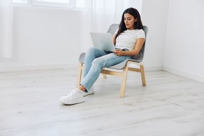 Young woman sitting on chair at home