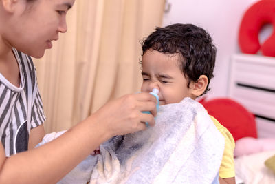 Mother blowing nasal spray in son nose