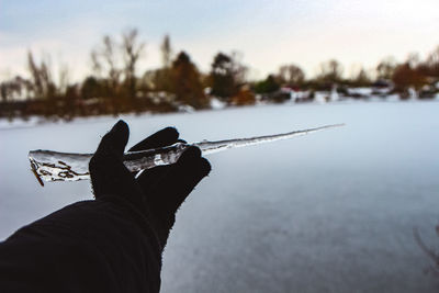 Person holding umbrella against sky during winter