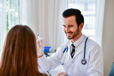 Smiling doctor injecting patient in hospital