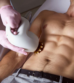 Man receiving fat reductive skin lifting body treatment on modern equipment at cosmetology clinic