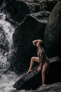 Portrait of young woman sitting on rock