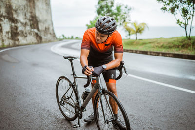 Exhausted bicycle rider with bicycle standing on road