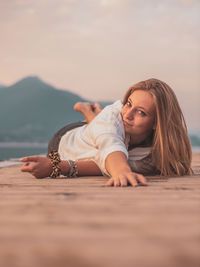 Portrait of woman lying down against sky during sunset