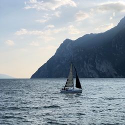 Sailboat sailing on sea against mountains