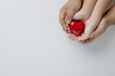 Close-up of hand holding heart shape over white background