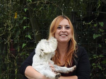 Portrait of smiling woman playing with dog