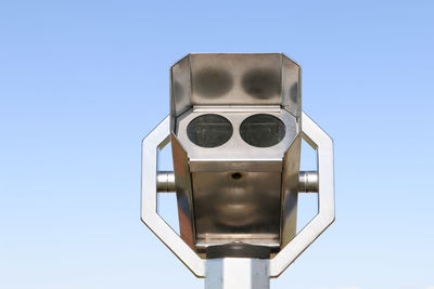 Low angle view of coin-operated binoculars against blue sky