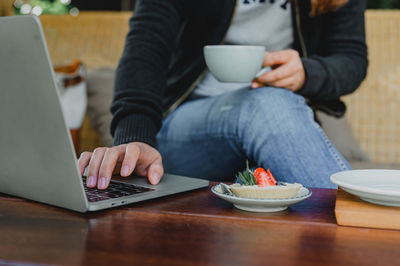 Midsection of man using mobile phone while sitting on table