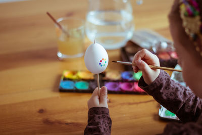 Kid painting easter egg with brush