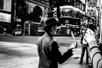 Cropped hand of person photographing woman on road