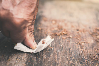 Cropped image of hand crushing cigarette