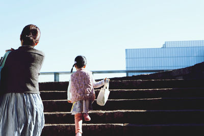 Rear view of women walking on staircase