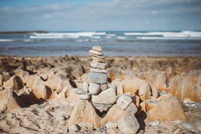 Close-up of stack of rocks at beach against sky