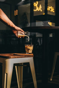Cropped hand pouring milk in coffee