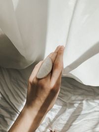 Close-up of human hand on bed