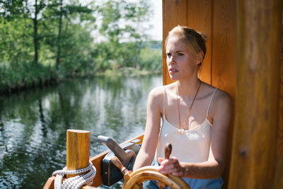 Woman sitting by wheel in boat on lake