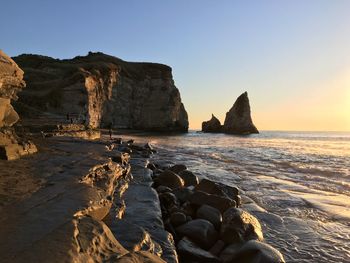 Rock formation in sea against clear sky