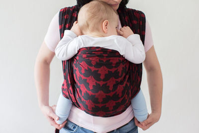 Midsection of woman carrying baby in harness