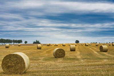 Hay bales on field against sky