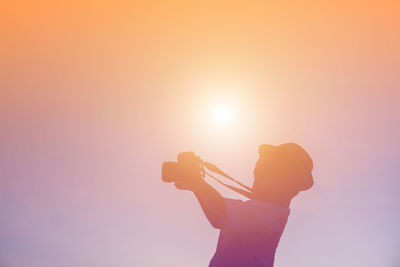 Silhouette man photographing against sky during sunset