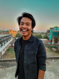 Portrait of smiling young man standing against sky