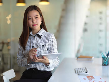 Young businesswoman holding digital tablet sitting at office