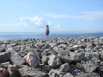 Rear view of girl standing on rock at beach