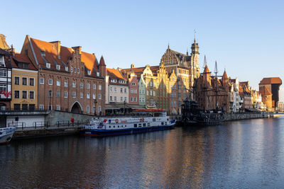 View of buildings by river against sky in city