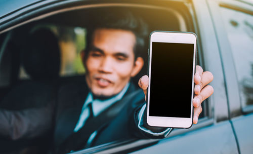 Businessman showing mobile phone while sitting in car