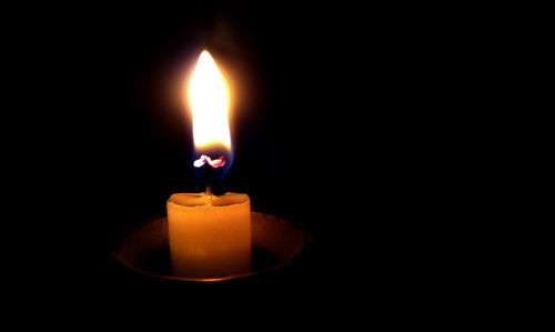 Close-up of lit  candle in dark room