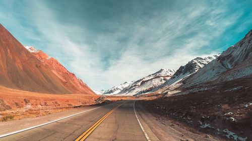 Road by mountains against sky