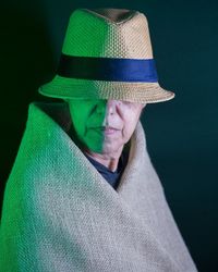 Portrait of man wearing hat against black background